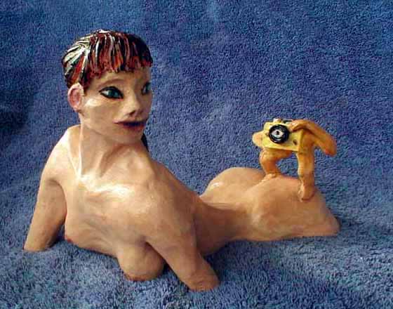 Sculpture: a yellow camera with arms and legs climbs over a model, taking pictures.