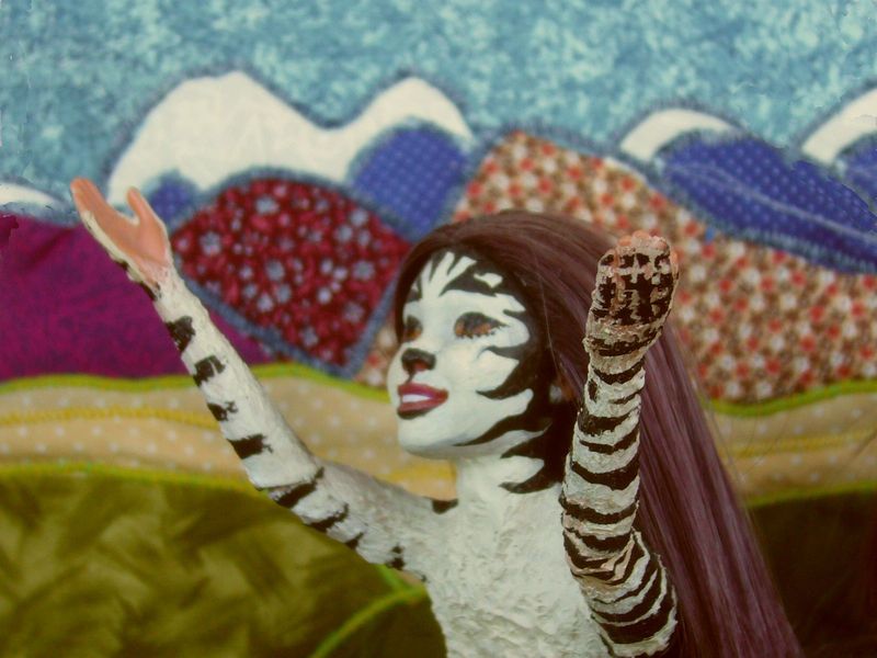 Suplica, an actress with zebra stripes, sings in front of quilted mountains; on Kakalea, a model of an Earthlike world full of Australias.