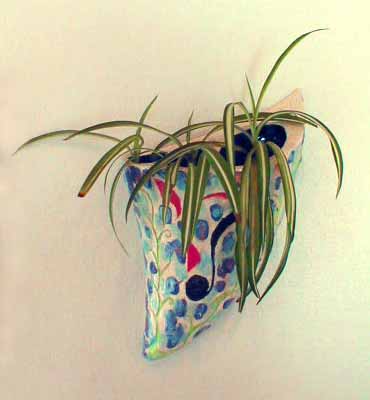 Three-holed sconce shaped like a shark tooth, with three spiderplants; glazed, for no reason, with musical notes. Click to enlarge.