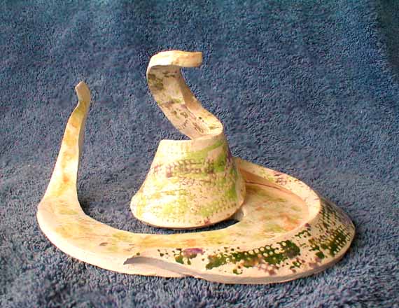 Side view, abstract ceramic snake made of a single clay disk cut in a spiral and lifted.